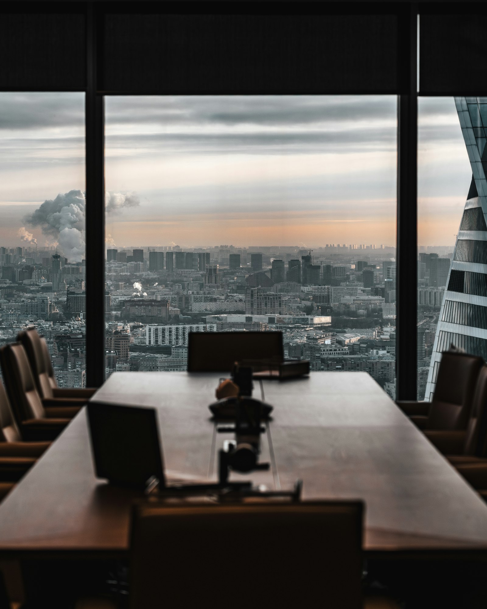 Quiet boardroom table beside floor-to-ceiling windows overlooking a city